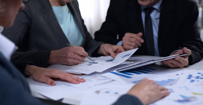 Government officials sitting around a table and discussing reports and diagrams