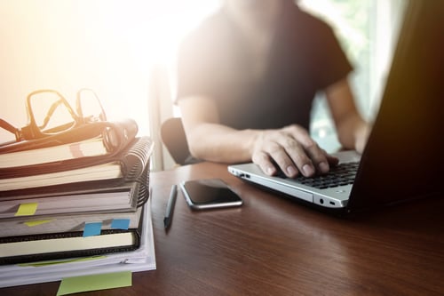 designer hand working with  digital tablet and laptop and notebook stack and eye glass on wooden desk in office-1